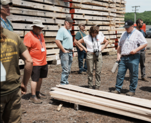 Joan Nichols and other attendees examine examine lumber Corey brides Ridel, of Ridel Portable Sawmills, had just sawn from graded logs. 